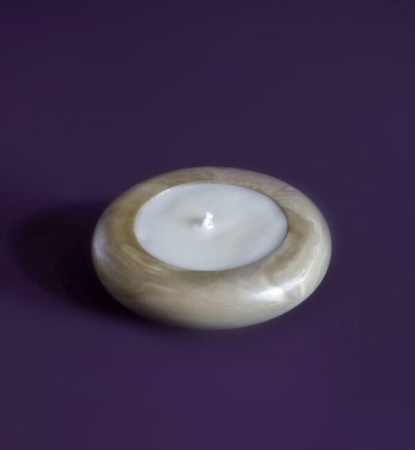 Vela artesanal Élore em formato de rosquinha, sem rótulo, sobre um fundo roxo minimalista.