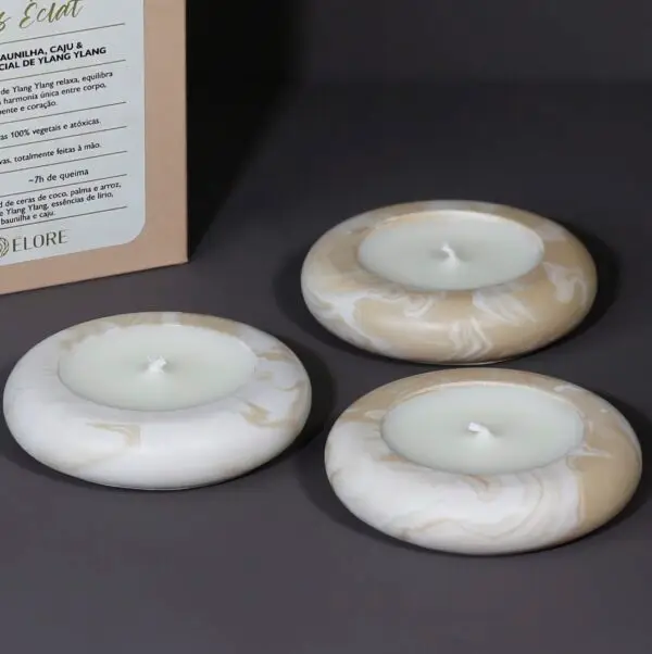 Kit Íris com 3 velas pequenas dispostas lado a lado, com caixa da Élore ao fundo.