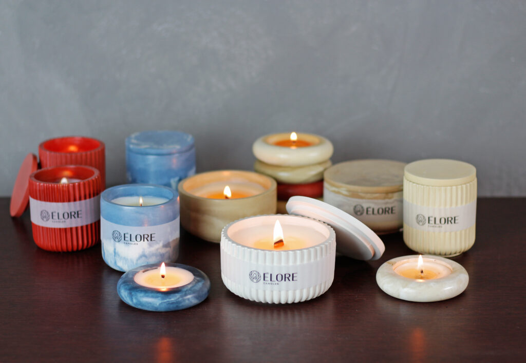 Conjunto de velas aromáticas artesanais Élore, em suportes de diferentes cores e texturas, todas acesas, criando uma atmosfera sofisticada.