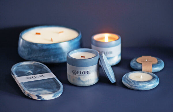 Conjunto de velas da coleção Minuit da Élore, incluindo diferentes tamanhos e formatos, em tons de azul marmorizado, dispostas sobre um fundo escuro sofisticado.
